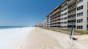 A beachfront hotel with multiple balconies, a sandy beach, and a clear blue sky. - Emerald Towers West 1003 - Sandy Toes (Fort Walton Beach)
