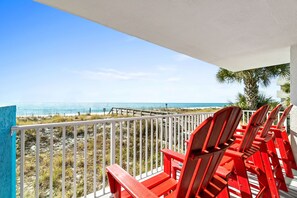 Ein Balkon mit roten Stühlen mit Blick auf einen Strand.