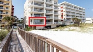 A beachfront hotel with multiple balconies, a wooden boardwalk, and a sandy beach. - Gulfside 203 - The Sandbar Escape (Fort Walton Beach)