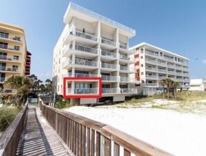 A beachfront hotel with multiple balconies, a wooden boardwalk, and a sandy beach. - Gulfside 203 - The Sandbar Escape (Fort Walton Beach)