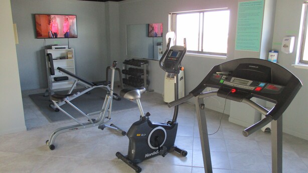 A gym with exercise equipment including a treadmill, stationary bike, and weight bench. - Gulfside 203 - The Sandbar Escape (Fort Walton Beach)
