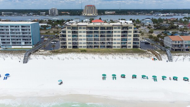 A beachfront hotel with multiple floors, a pool, and beach umbrellas. - Emerald Towers West 5004 - Beachside Memories (Fort Walton Beach)