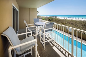 A balcony with a pool, chairs, and a view of the beach. - Summerlin 103 - Shell Seekers Retreat (Fort Walton Beach)