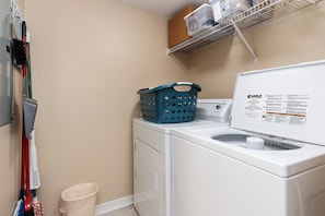A laundry area with a washing machine, a drying rack, and a basket. - Summerlin 103 - Shell Seekers Retreat (Fort Walton Beach)