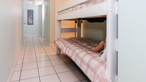 A narrow hallway with a bunk bed on the right, a door at the end, and a small window on the left. - Emerald Towers West 2004 - Palms & Paradise (Fort Walton Beach)