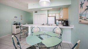 A compact kitchen with a central island, white cabinets, and a microwave. - Emerald Towers West 2004 - Palms & Paradise (Fort Walton Beach)