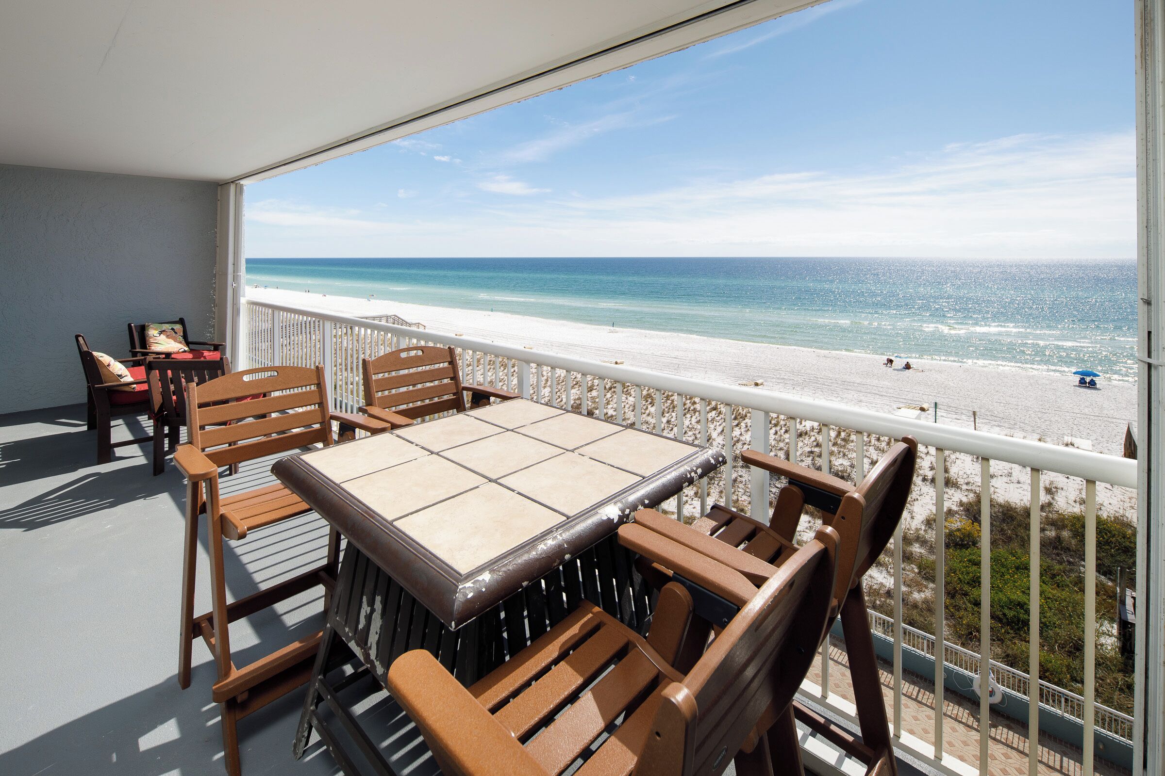 A balcony with a table and chairs overlooking a beach.