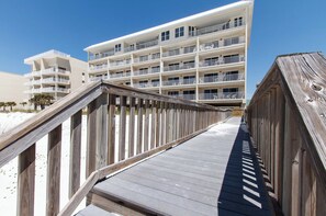 Eine Holzpromenade führt zu einem mehrstöckigen Hotel mit Balkonen.