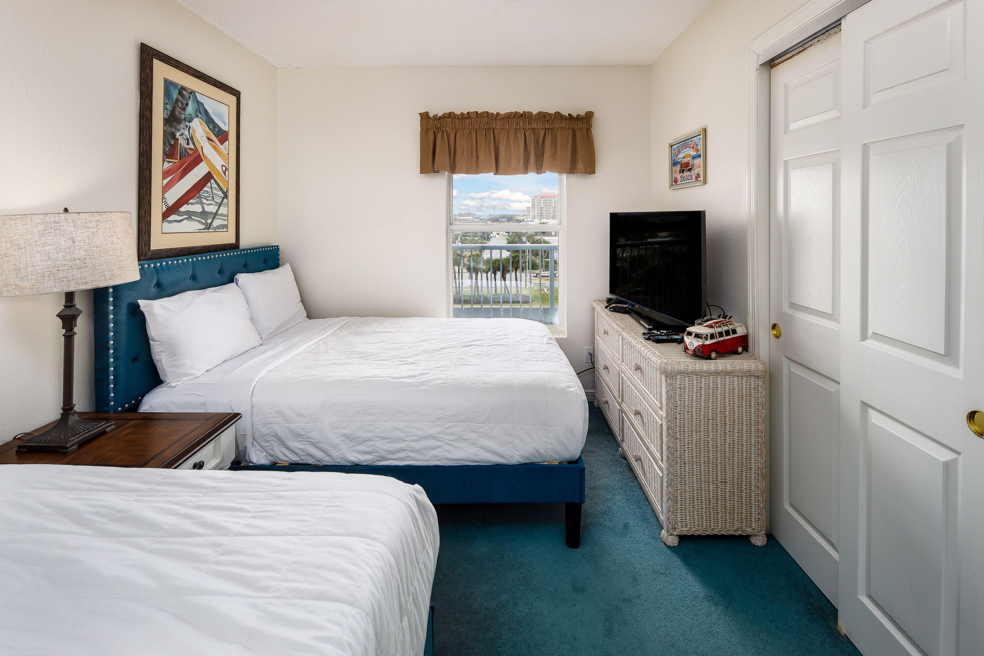 Une chambre d’hôtel avec deux lits, une télévision, une commode et une fenêtre donnant sur un paysage agréable.