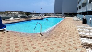 En swimmingpool med solstolar och en kakelbeklädd terrass.