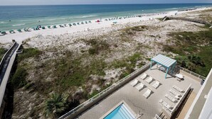 A beach view with a pool area, lounge chairs, and umbrellas. - Gulf Dunes 504 - Emerald Sea Oasis (Fort Walton Beach)