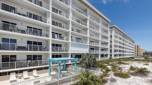 A multi-story hotel with balconies, outdoor seating, and a beach view. - Gulf Dunes 504 - Emerald Sea Oasis (Fort Walton Beach)