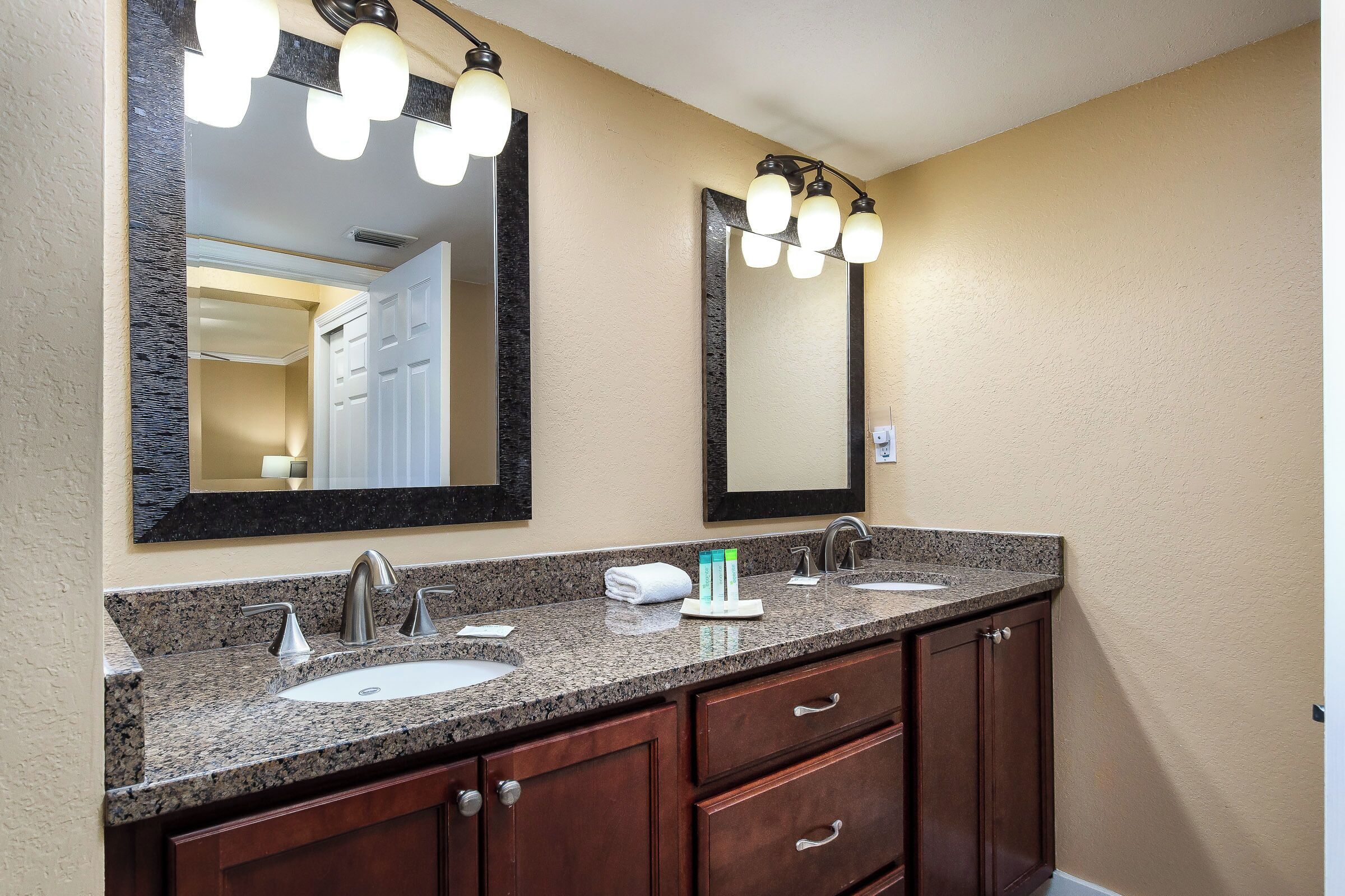 A bathroom with two sinks, a large mirror, and a vanity with drawers.