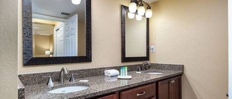 A bathroom with two sinks, a large mirror, and a vanity with drawers.