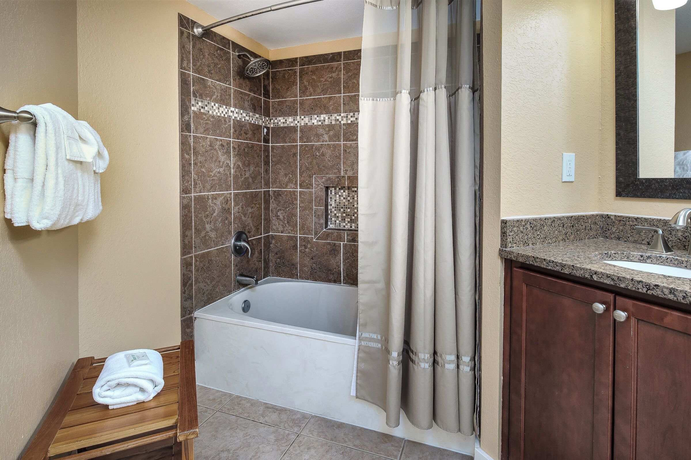 A bathroom with a bathtub, shower, and a vanity with a sink.