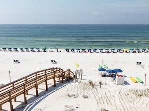 Ein Strand mit einer Holzpromenade, die zu Strandstühlen und Sonnenschirmen führt.