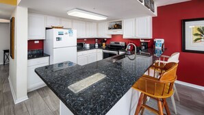 Eine moderne Küche mit weißen Schränken, einer Granitarbeitsplatte und einer roten Akzentwand.