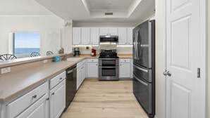 A modern kitchen with white cabinets, stainless steel appliances, and a wooden countertop. - Gulf Dunes 617 - Sand Dollar Daze (Fort Walton Beach)