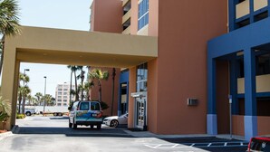 Un hôtel doté d’un grand parking, d’une entrée couverte et d’un bâtiment à plusieurs étages avec des balcons.