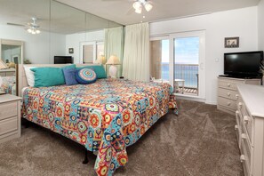 Een slaapkamer met een groot bed, een televisie, een dressoir en een balkon met uitzicht.