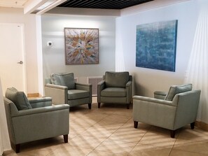 A room with four grey armchairs, a small table, and two abstract paintings on the walls. - Islander 7010 - Coastal Charm (Fort Walton Beach)