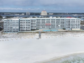 Un hôtel situé en bord de mer, doté de nombreux balcons, d’une piscine et donnant sur la plage.