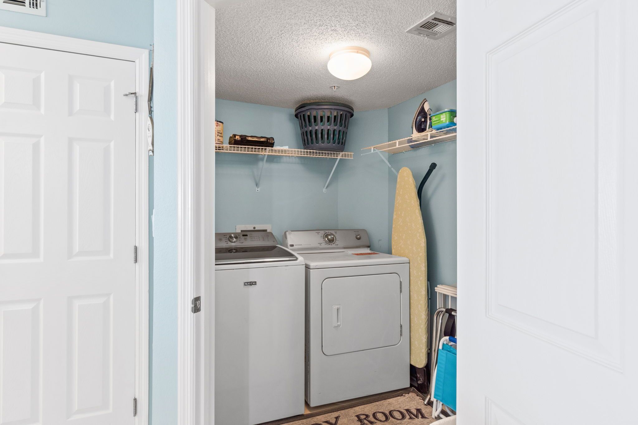 Une buanderie équipée d’un lave-linge, d’un sèche-linge et d’une planche à repasser.