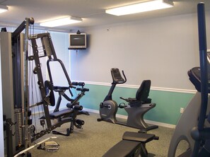 A gym with exercise equipment, a television, and a window with blinds. - Island Princess 309 - Splash of Paradise (Fort Walton Beach)