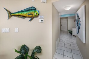 A hallway with a fish mural, a thermostat, and a plant. - Islander 6004 by Brooks and Shorey Resorts (Fort Walton Beach)
