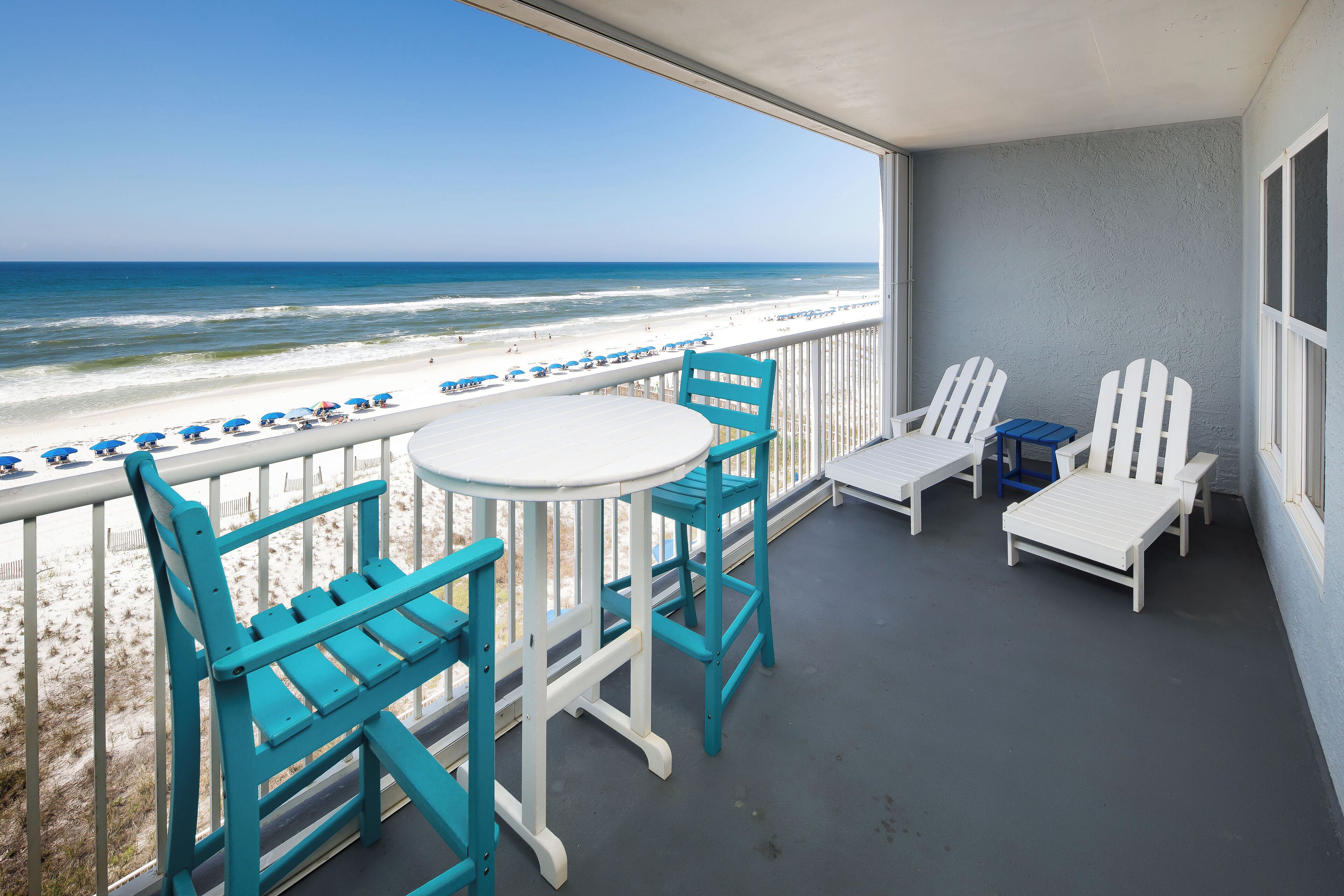 Un balcone con vista sulla spiaggia, con un tavolo e delle sedie.