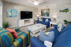 A living room with a television, sofa, and coffee table. - Islander 6004 by Brooks and Shorey Resorts (Fort Walton Beach)