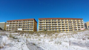 Un hotel de varios pisos y balcones, rodeado por un paisaje arenoso con vegetación escasa.