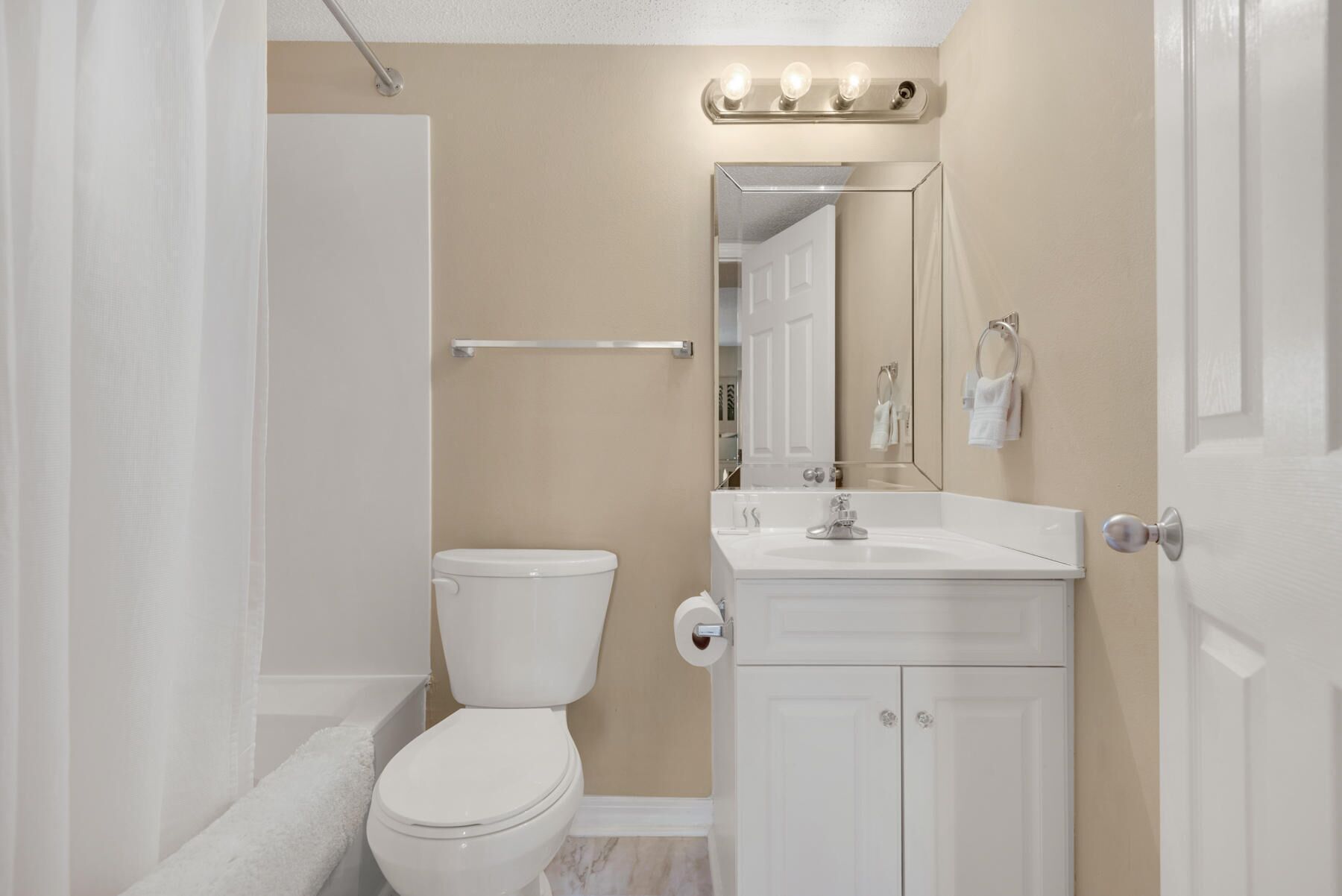 Een badkamer met toilet, wastafel, spiegel en handdoekhouder.