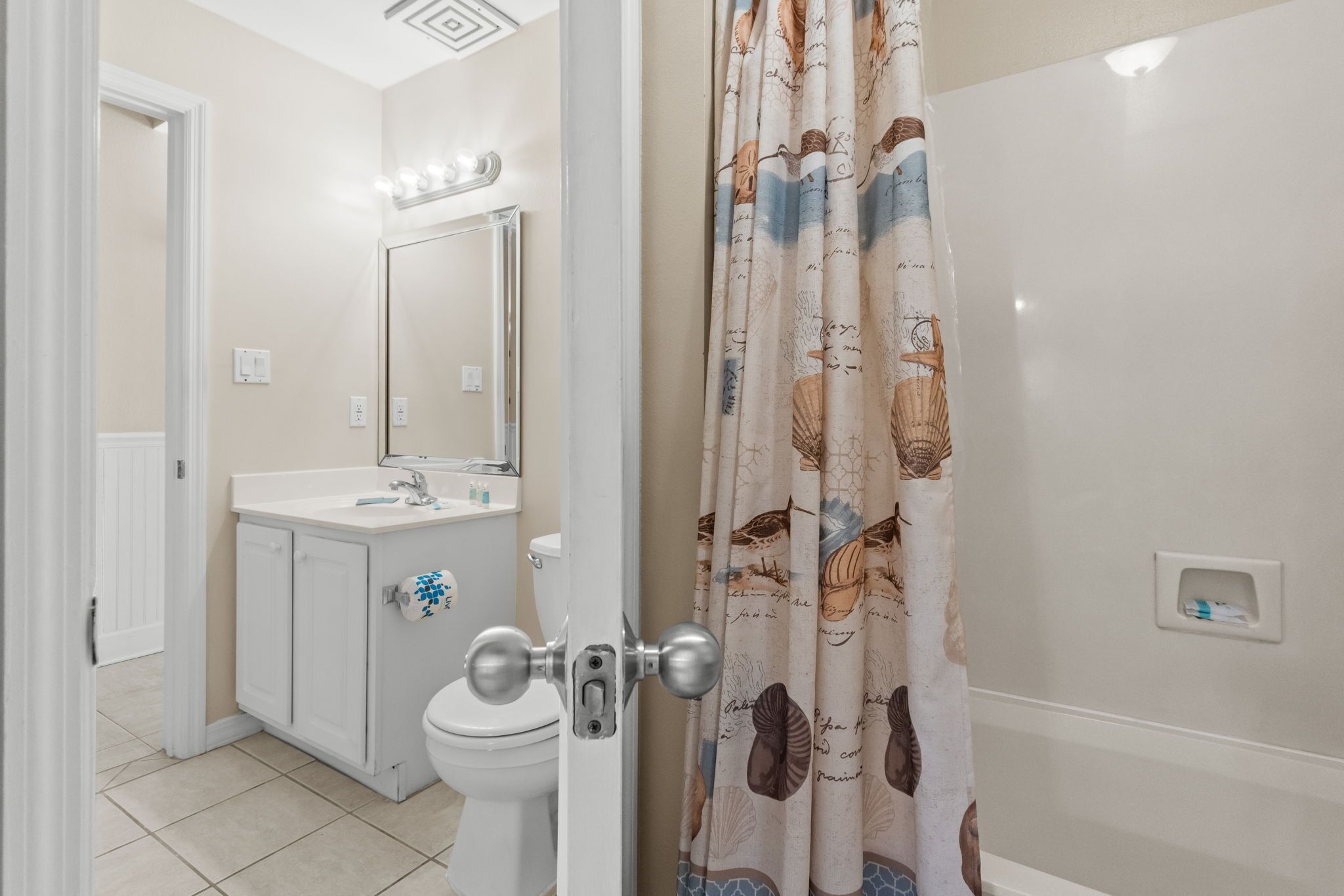 A bathroom with a toilet, sink, mirror, and shower curtain.