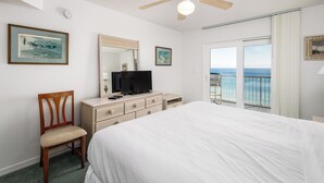 Une chambre à coucher comprenant un lit, une télévision, une commode, une chaise et un balcon avec vue sur l’océan.