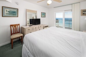 Ein Schlafzimmer mit Bett, Fernseher, Kommode, Stuhl und einem Balkon mit Meerblick.
