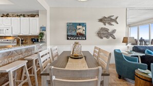 Un comedor con una mesa de madera, sillas blancas y un centro decorativo.