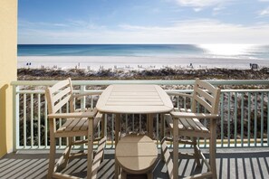 A balcony with a table and chairs overlooking a beach. - Pelican Isle 311 - Oceans Embrace (Fort Walton Beach)