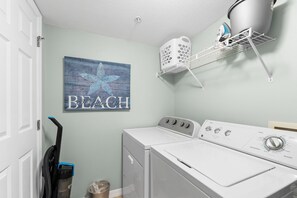 A laundry area with a washing machine, dryer, and a wall-mounted drying rack. - Gulf Dunes 416 - Ocean's Edge (Fort Walton Beach)