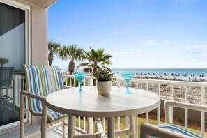 A balcony with a round table, striped chairs, and two blue cocktail glasses. - Island Princess 213 - Starlight Retreat (Fort Walton Beach)