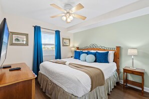 Ein Schlafzimmer mit einem Bett, einem Schreibtisch, einem Deckenventilator und einem Nachttisch.