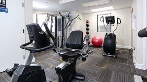 Una palestra con attrezzature cardio, macchine per pesi e palle da ginnastica.