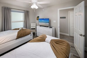 Ein Schlafzimmer mit zwei Betten, einem Fernseher, einem Schreibtisch und einem 'welcome'-Schild.