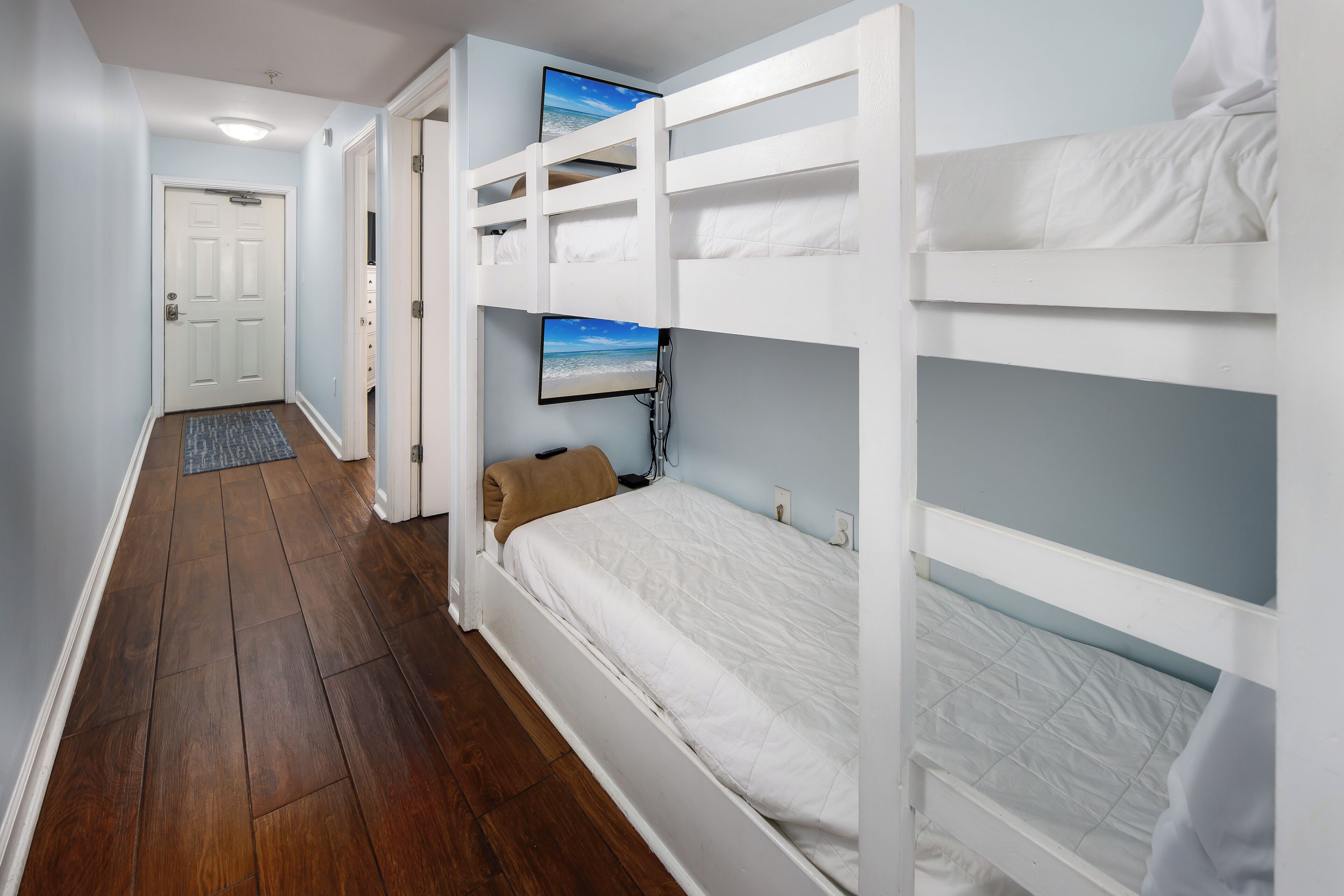 Una habitación con literas, una puerta y un pasillo.
