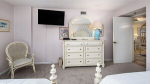 A bedroom with two beds, a dresser, a television, and a chair. - Surf Dweller 603 - Swaying Palms (Fort Walton Beach)
