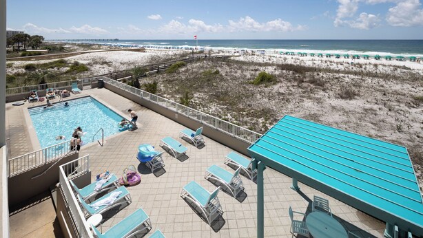 A rooftop pool area with lounge chairs and a view of the beach and ocean. - Gulf Dunes 207 - Blue Skies & Beach Vibes (Fort Walton Beach)