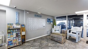 A reception area with a bulletin board, a desk, a chair, and a view of the parking area. - Gulf Dunes 207 - Blue Skies & Beach Vibes (Fort Walton Beach)