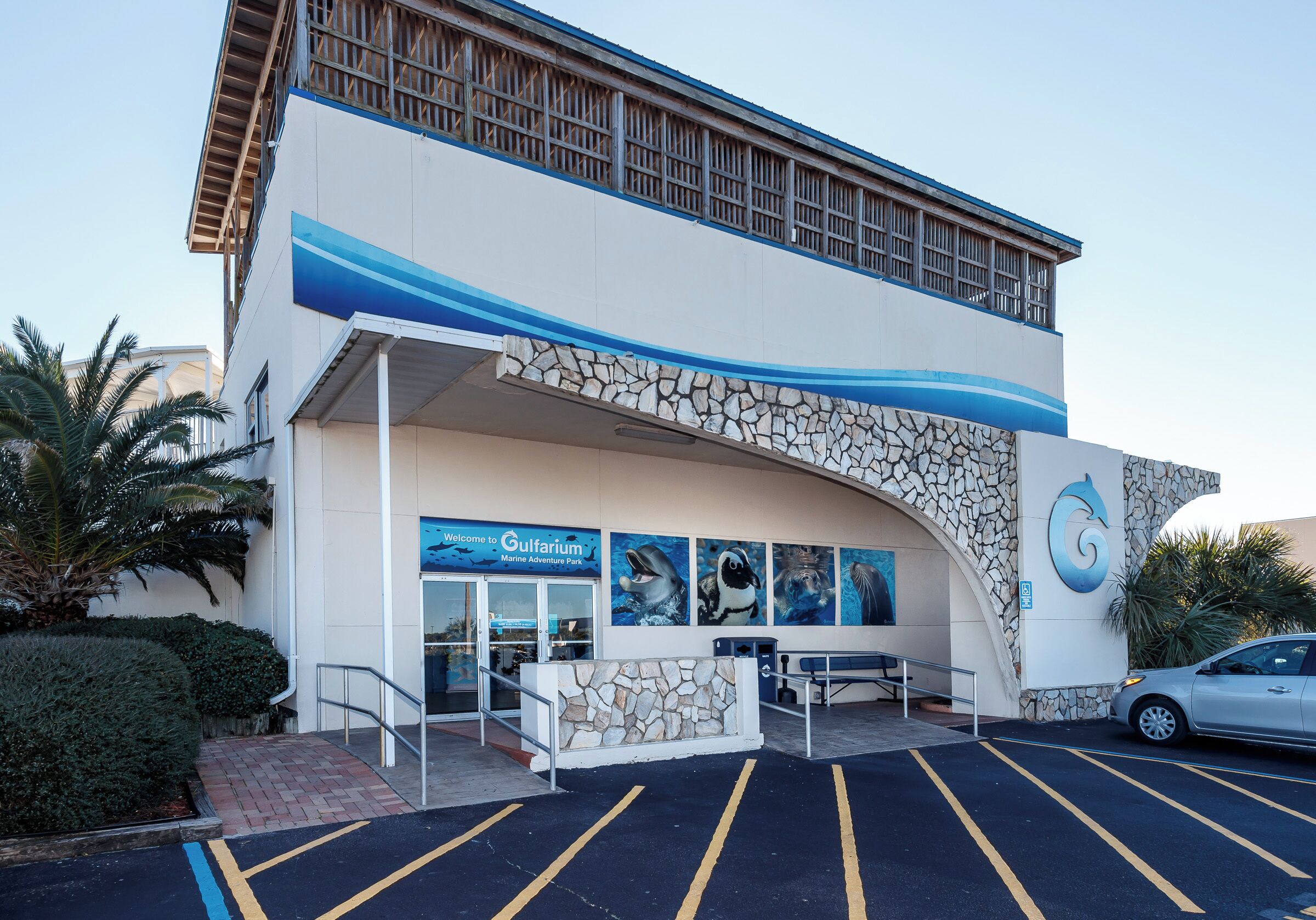 Ein Gebäude mit einer Stein-Fassade, einer blauen und weißen Farbgebung und einem Schild mit der Aufschrift 'Welcome to Gulfarium Marine Adventure Park'.