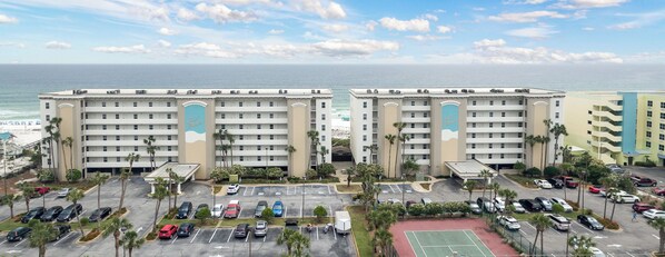 A hotel with multiple floors, a parking lot, and a view of the ocean. - Gulf Dunes 412 - Sunset Fiesta (Fort Walton Beach)