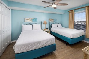 A hotel room with two beds, a ceiling fan, a window with curtains, and a view of the city. - Gulf Dunes 412 - Sunset Fiesta (Fort Walton Beach)
